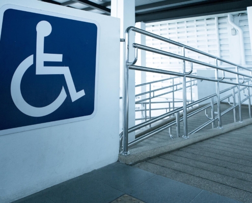 Image of a handicap sign next to a ramp with guardrails.