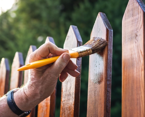 Image of a person painting a residential fence